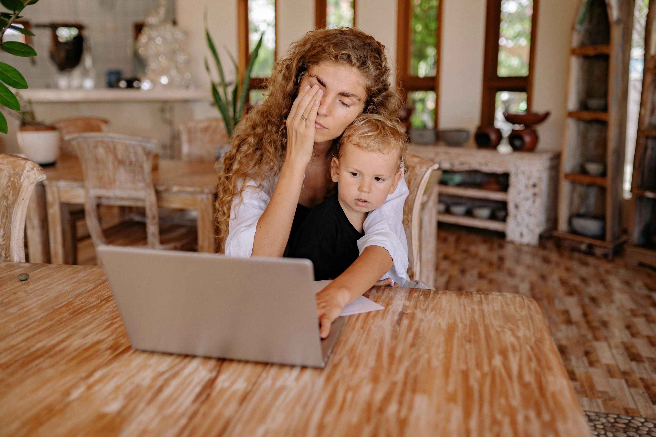 tired mom on computer with child in her lap